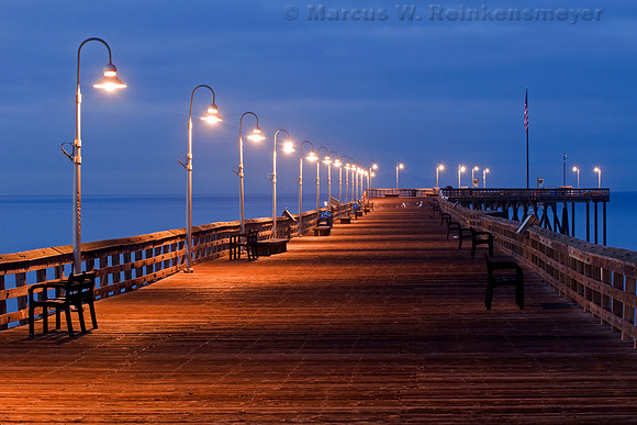 Lighted wooden walkway and benches at Ventura Pier at night, Ventura, California.