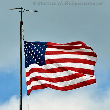 American Flag and weather vane, blowing in the wind, at the beach, South Haven, Michigan.