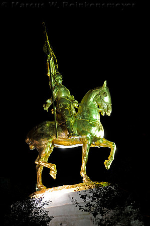 Night photo of the golden bronze statue of Joan of Arc, a gift from the people of France to the City of New Orleans in 1972.