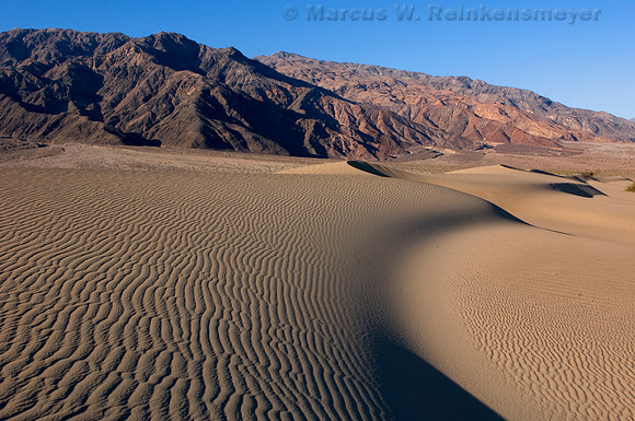 Dramatic sand dune formations flanked by the Panimint Mountains, at Mesquite Flat Dunes in Death Valley National Park.