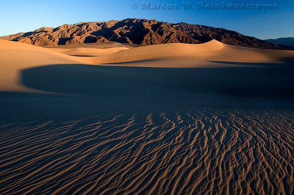 Dramatic sand dune formations flanked by the Panimint Mountains, at Mesquite Flat Dunes in Death Valley National Park.