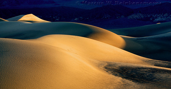 Warm sun rays and long shadows create a visual delight at Mesquite Flat Dunes, a large expanse of dunes in Death Valley National Park, California.