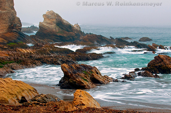 Shrouded in heavy fog, the rocky beach at Montana de Ore State Park, California.